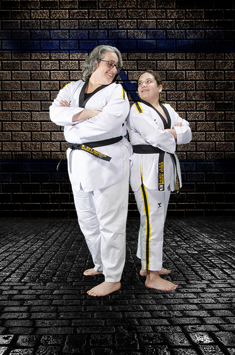 Mother and daughter in taekwondo attire, standing back-to-back.